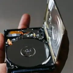Otwarty dysk HDD, trzymany w dłoni, ukazuje błyszczące talerze. To serce największego dysku HDD, gotowe do przechowywania danych.