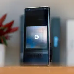 Smartfon z ekranem prezentującym układ Google Tensor G5. Obok stoi doniczka z czerwoną rośliną.