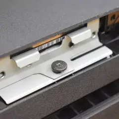 Metalowa ramka mocująca dysk SSD w konsoli PS4, widoczny wkręt.