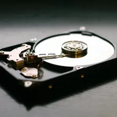 Wnętrze dysku twardego, widoczna błyszcząca płyta i ramię odczytujące. Idealny **hd tune** dla miłośników technologii.