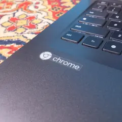 Naklejka z logo Chrome na ciemnym laptopie, obok klawiatury. System Chrome działa płynnie.