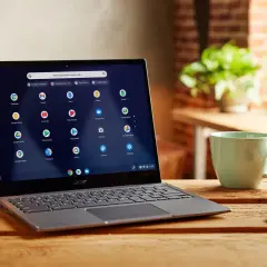 Laptop z systemem Chrome OS instalacja. Na ekranie widoczne ikony aplikacji Google. Obok kubek i klucze.