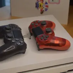 Dwa kontrolery, czarny i czerwony, leżą na konsoli PS4. Idealne na premierę PS4!