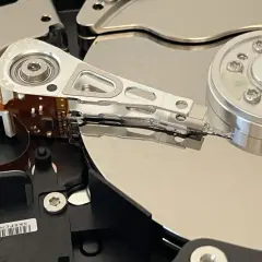 Wnętrze dysku twardego, przygotowanego do testu ssd. Widoczne talerze, głowice i mechanizm pozycjonujący.
