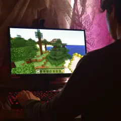 Gracz steruje postacią w grze Minecraft, która działa dzięki technologii directx 9. Widać jego dłoń na podświetlanej klawiaturze.