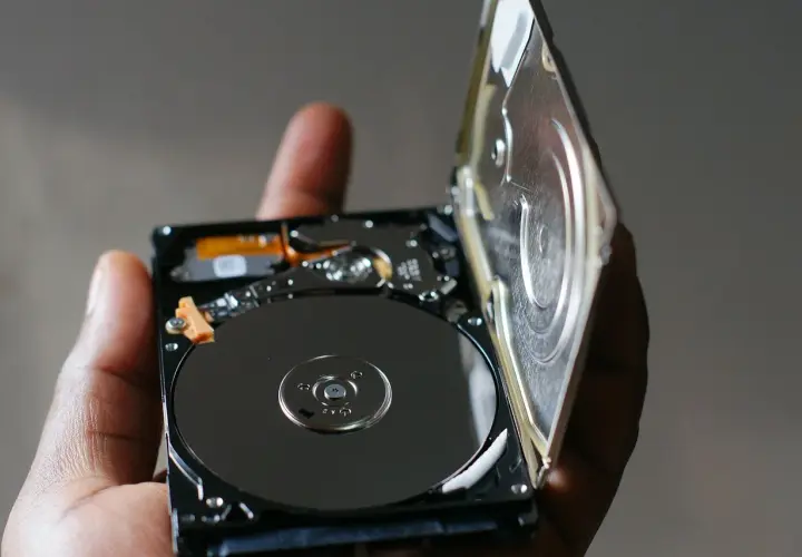 Otwarty dysk HDD, trzymany w dłoni, ukazuje błyszczące talerze. To serce największego dysku HDD, gotowe do przechowywania danych.