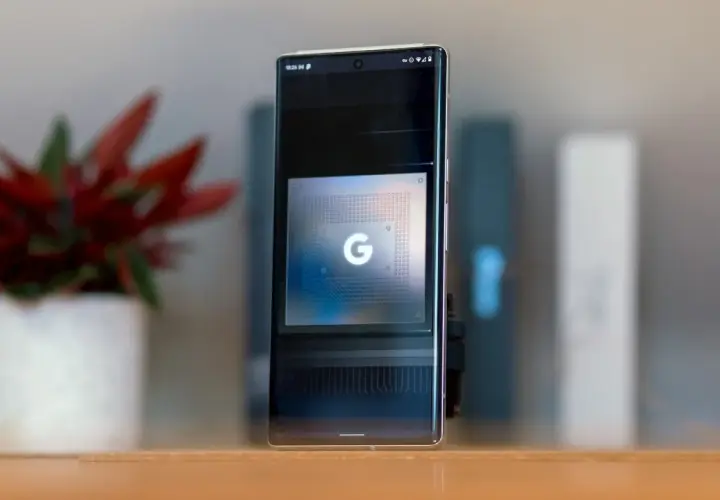 Smartfon z ekranem prezentującym układ Google Tensor G5. Obok stoi doniczka z czerwoną rośliną.