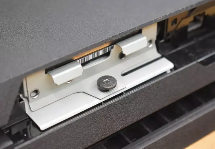 Metalowa ramka mocująca dysk SSD w konsoli PS4, widoczny wkręt.