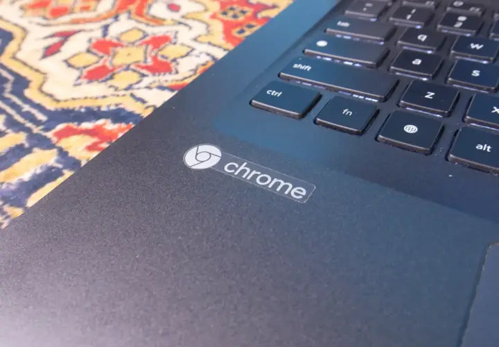 Naklejka z logo Chrome na ciemnym laptopie, obok klawiatury. System Chrome działa płynnie.