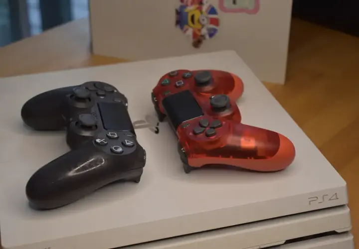 Dwa kontrolery, czarny i czerwony, leżą na konsoli PS4. Idealne na premierę PS4!