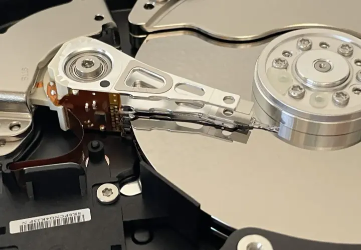 Wnętrze dysku twardego, przygotowanego do testu ssd. Widoczne talerze, głowice i mechanizm pozycjonujący.