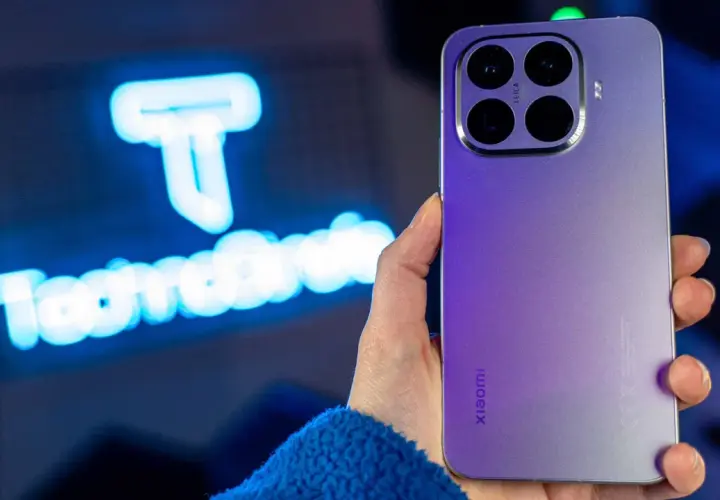 Fioletowy Xiaomi 15T Pro z potrójnym aparatem Leica w dłoni, na tle niebieskiego logo.