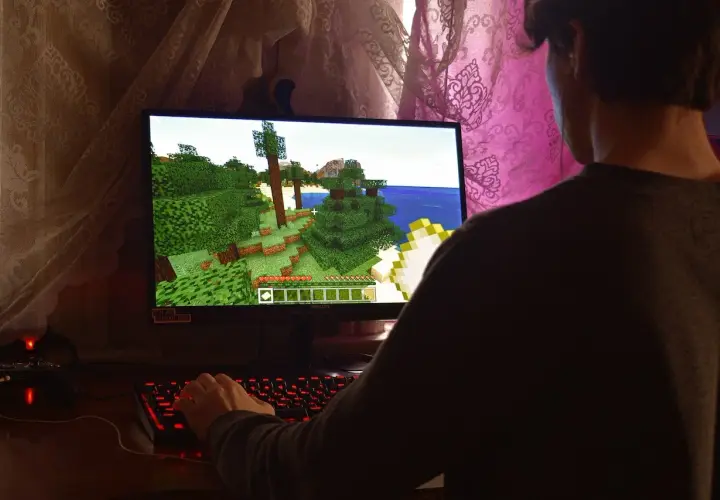 Gracz steruje postacią w grze Minecraft, która działa dzięki technologii directx 9. Widać jego dłoń na podświetlanej klawiaturze.