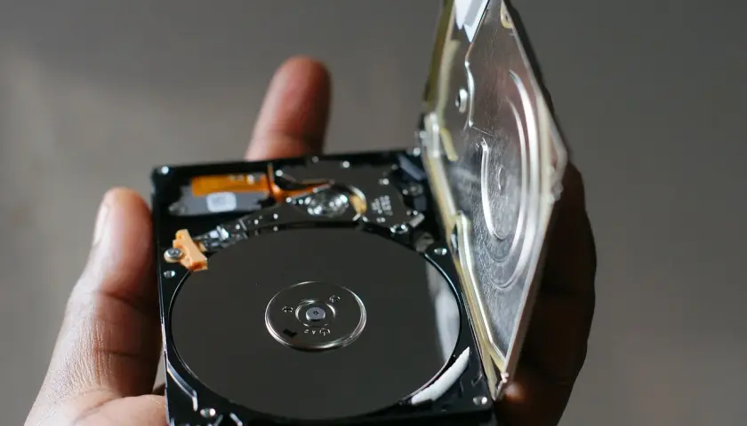 Otwarty dysk HDD, trzymany w dłoni, ukazuje błyszczące talerze. To serce największego dysku HDD, gotowe do przechowywania danych.