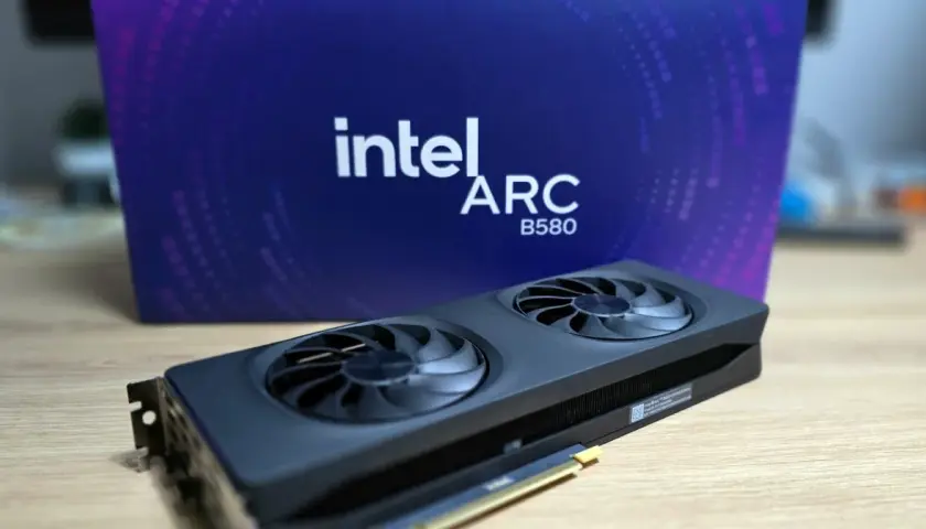 Karta graficzna Intel Arc A580 z dwoma wentylatorami na tle fioletowego pudełka z logo Intel Arc.