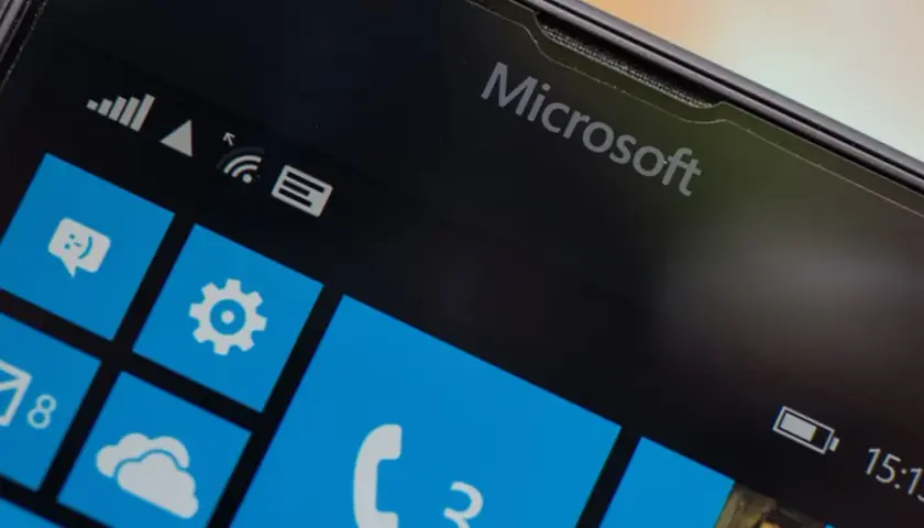 Ekran telefonu z logo Microsoft i kafelkami interfejsu Windows Mobile. Widoczne ikony wiadomości, ustawień, poczty i telefonu.