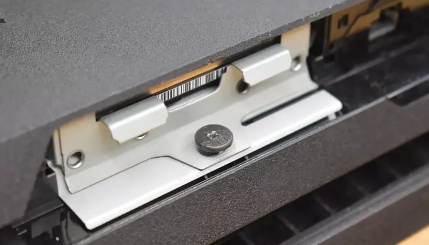 Metalowa ramka mocująca dysk SSD w konsoli PS4, widoczny wkręt.