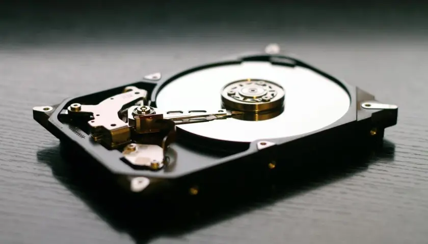 Wnętrze dysku twardego, widoczna błyszcząca płyta i ramię odczytujące. Idealny **hd tune** dla miłośników technologii.