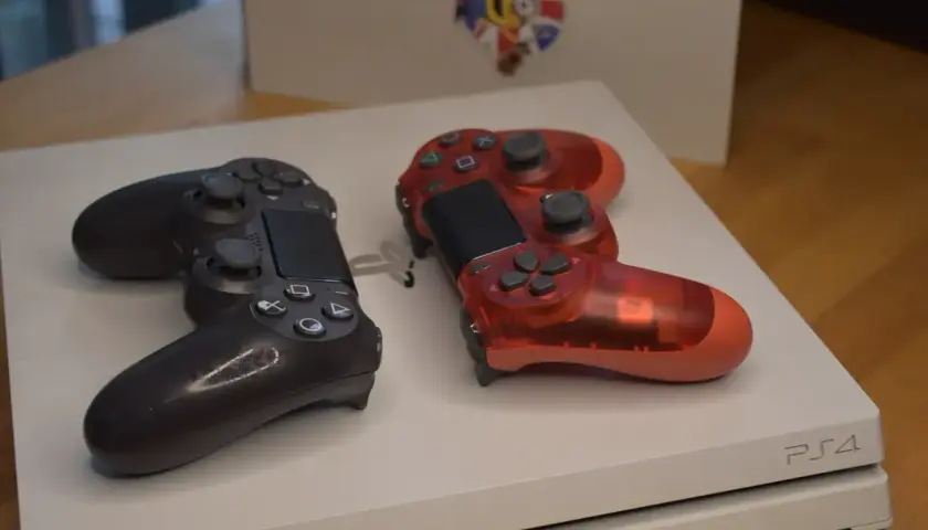 Dwa kontrolery, czarny i czerwony, leżą na konsoli PS4. Idealne na premierę PS4!
