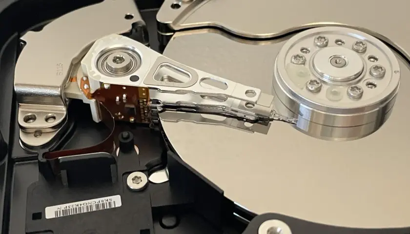 Wnętrze dysku twardego, przygotowanego do testu ssd. Widoczne talerze, głowice i mechanizm pozycjonujący.