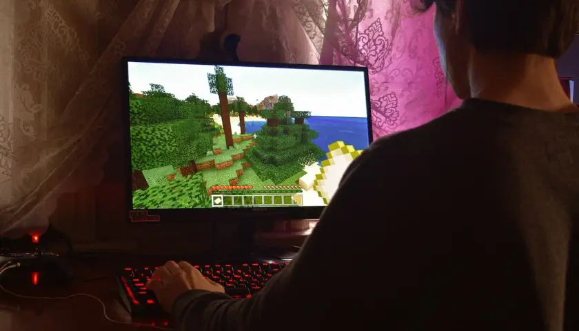 Gracz steruje postacią w grze Minecraft, która działa dzięki technologii directx 9. Widać jego dłoń na podświetlanej klawiaturze.