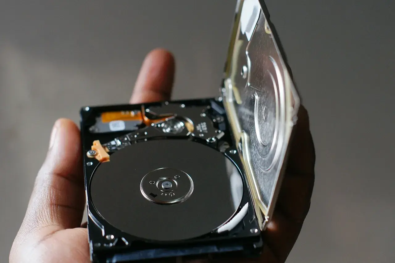 Otwarty dysk HDD, trzymany w dłoni, ukazuje błyszczące talerze. To serce największego dysku HDD, gotowe do przechowywania danych.