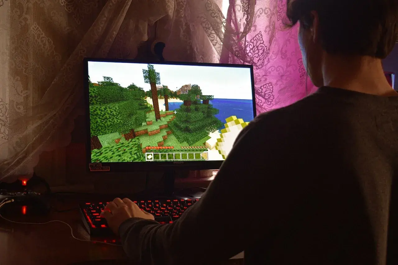 Gracz steruje postacią w grze Minecraft, która działa dzięki technologii directx 9. Widać jego dłoń na podświetlanej klawiaturze.
