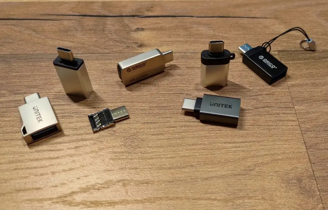 R&oacute;żne rodzaje pendrive'&oacute;w i adapter&oacute;w USB-C na drewnianym tle.
