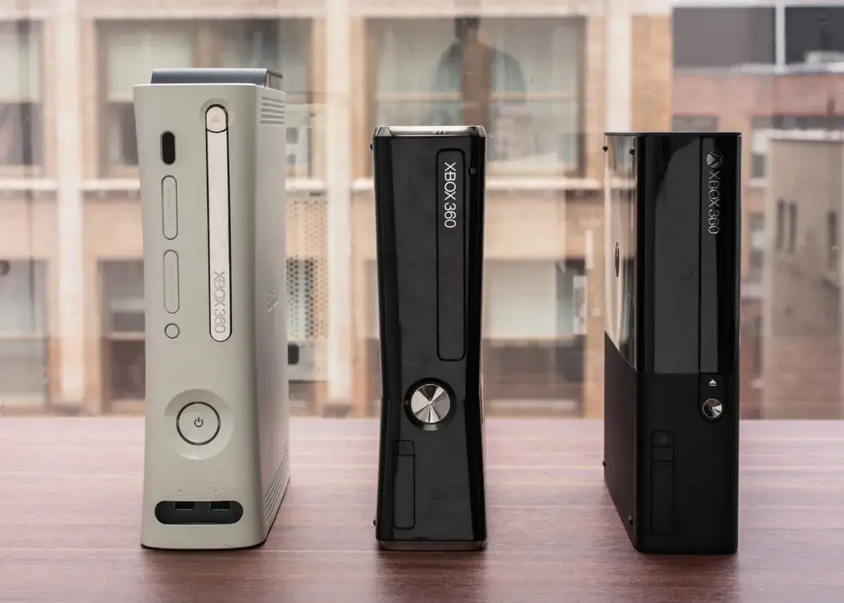 Trzy xbox modele po kolei: biały, czarny smukły i czarny z błyszczącym frontem.