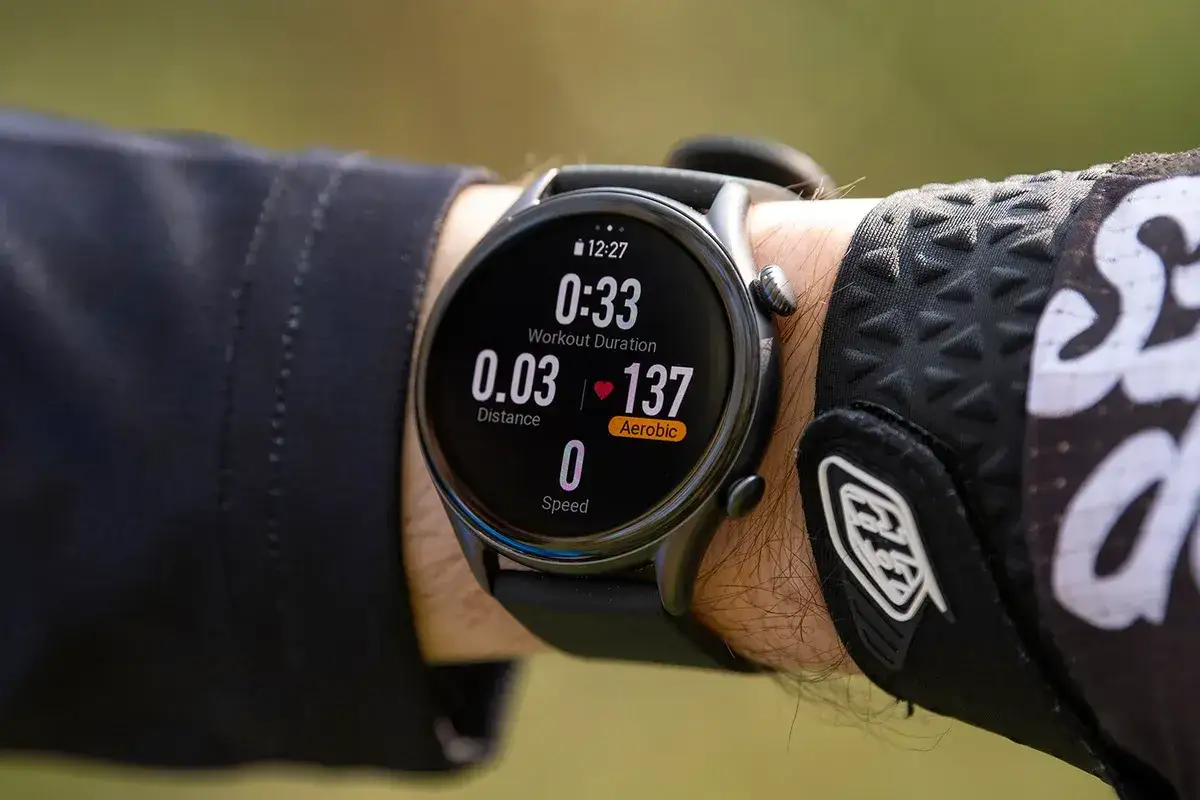 Nadgarstek w rękawiczce rowerowej, na kt&oacute;rym widnieje smartwatch gtr 3 pro, pokazujący czas treningu, dystans i tętno.